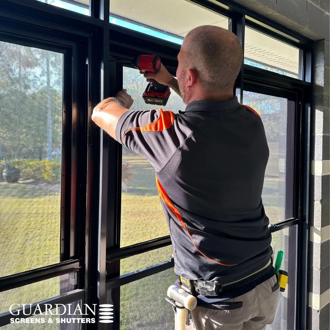Clinton fitting a Crimsafe window screen, drill in hand