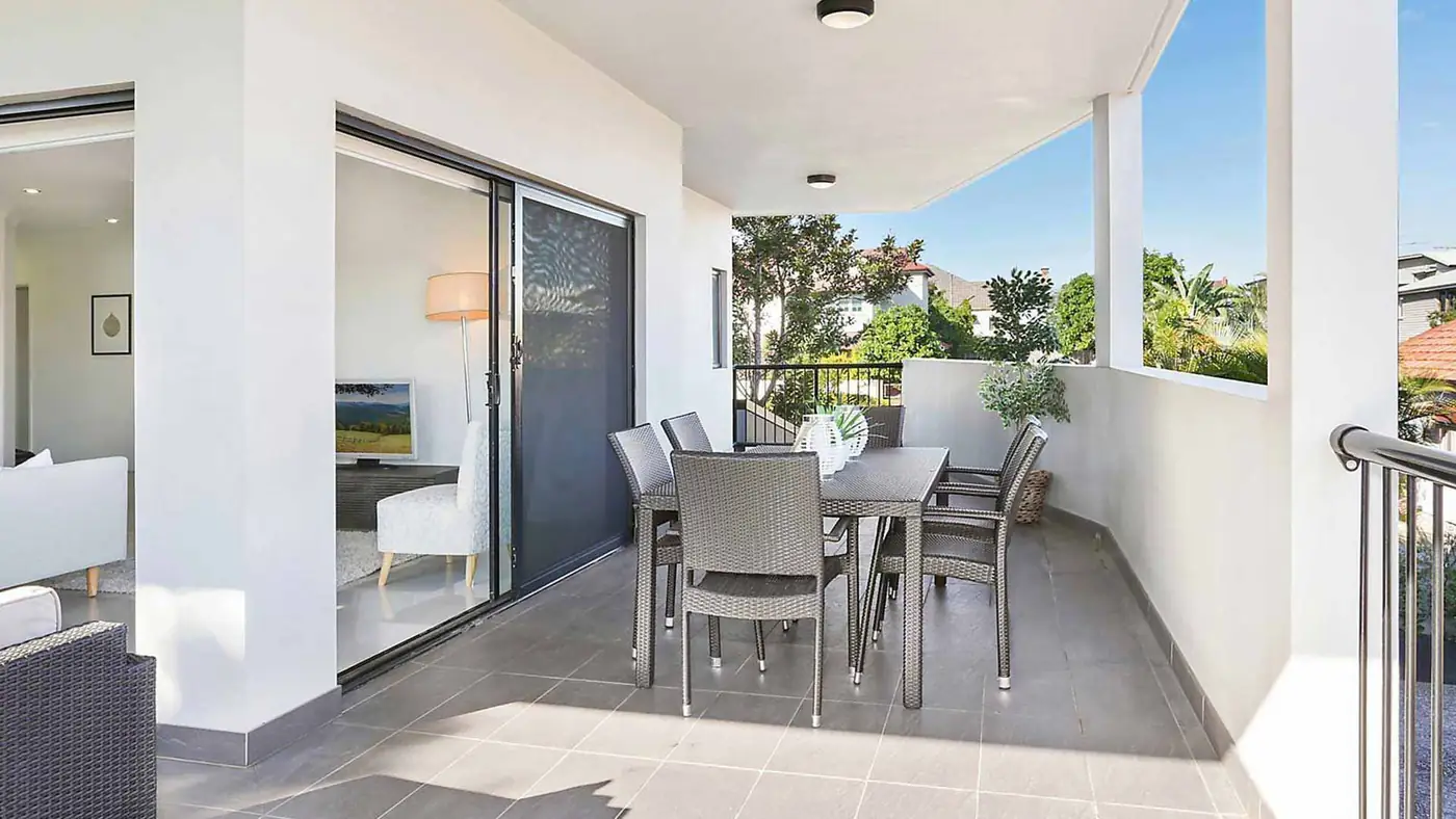 A Brisbane patio with the sliding screen door open to the living room, table and chairs set out under cover