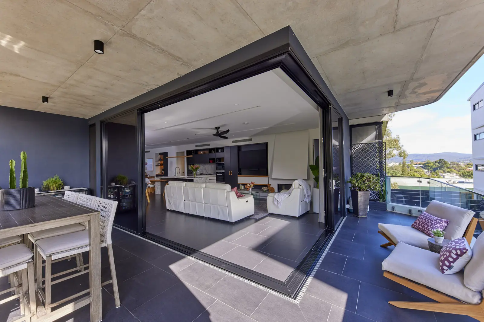 A Crimsafe corner stacking door slid fully open, the living room and the balcony one space